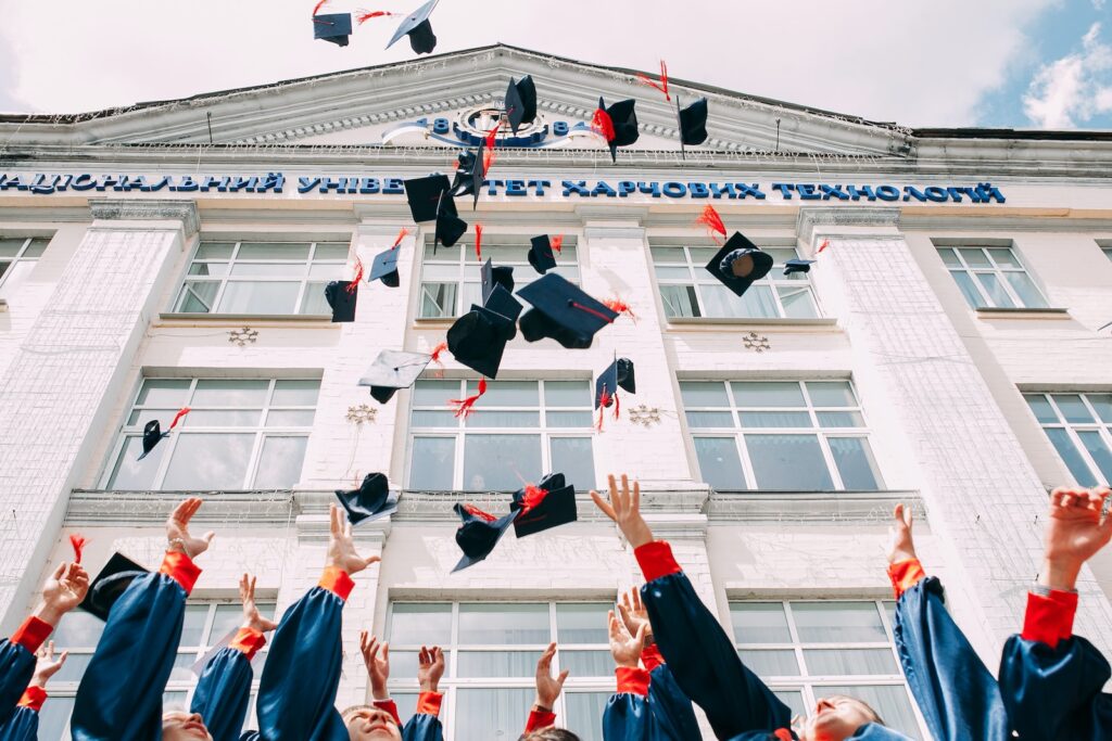 group of fresh graduates students throwing their academic hat in the air